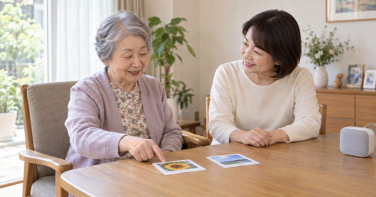 自宅の食卓で高齢女性が写真カードを指し、家族がゆっくり会話を待つ生成イメージ