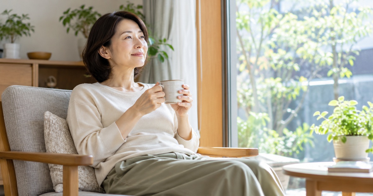 自宅の椅子でカップを持ち休む女性