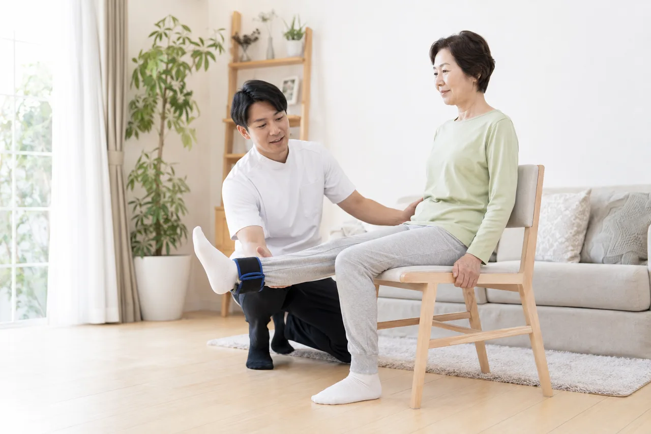 変形性膝関節症の人が椅子で膝伸展の筋力トレーニングを行う場面